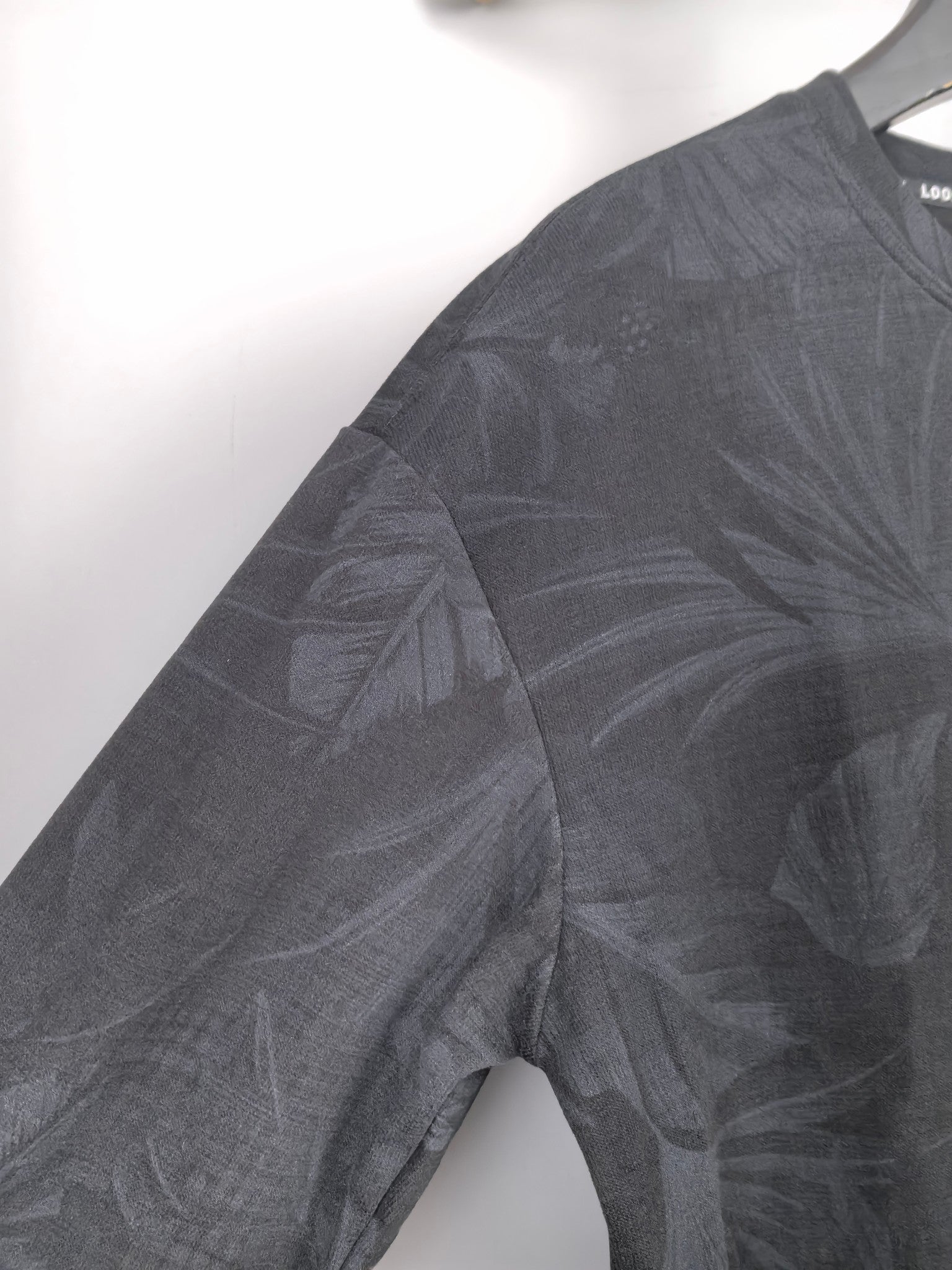 Long-sleeve sweatshirt sleeve with dark gray leaf print, crew neck edge.