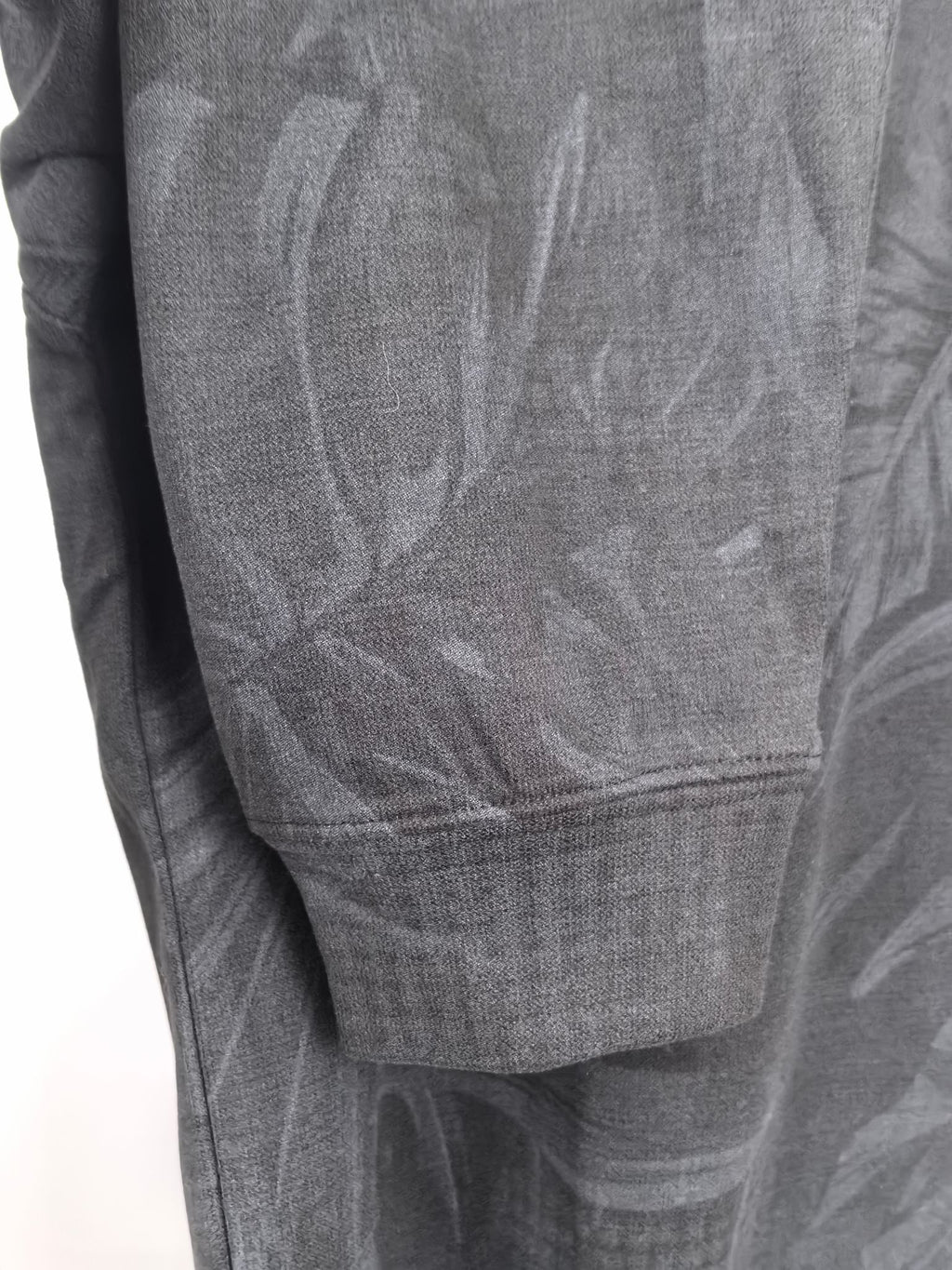 Long-sleeve sweatshirt front panel with dark gray leaf print and ribbed hem.