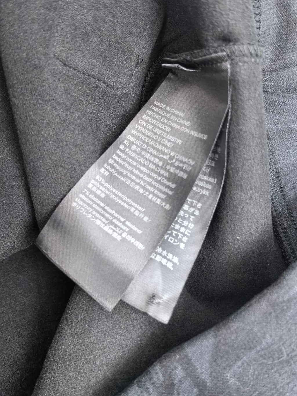 Long-sleeve sweatshirt with interior care label tag on dark gray fabric.