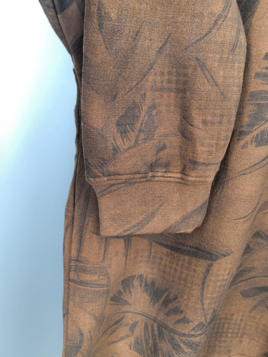 Brown long-sleeve top with dark leaf print and ribbed cuffs