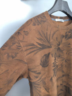 Brown long-sleeve top with dark tropical leaf print, close-up of sleeve and shoulder