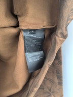 Inner care label on brown long-sleeve top, printed text on fabric seam
