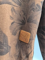 "Miss Dior" leather-look patch on brown long-sleeve top with dark leaf print