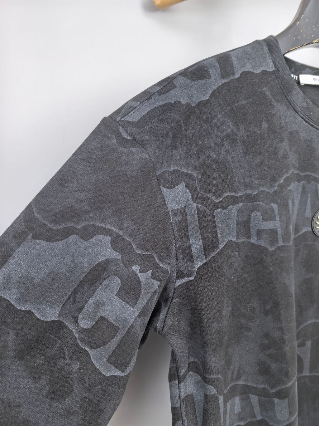 Dark gray crewneck sweatshirt sleeve with camo-style text graphic