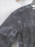 Dark gray crewneck sweatshirt sleeve with camo-style text graphic