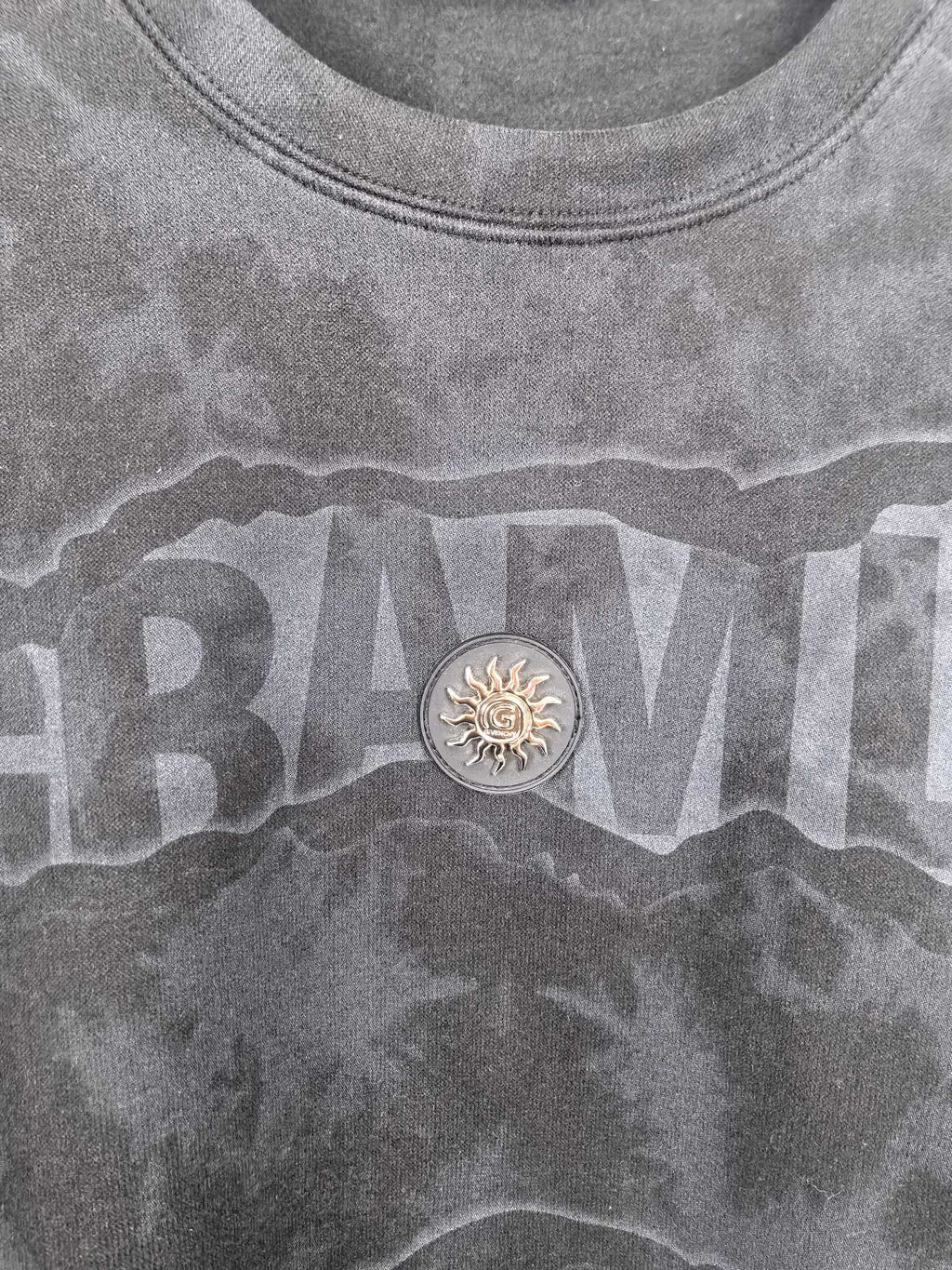 Dark gray crewneck sweatshirt with large front text graphic and round emblem detail
