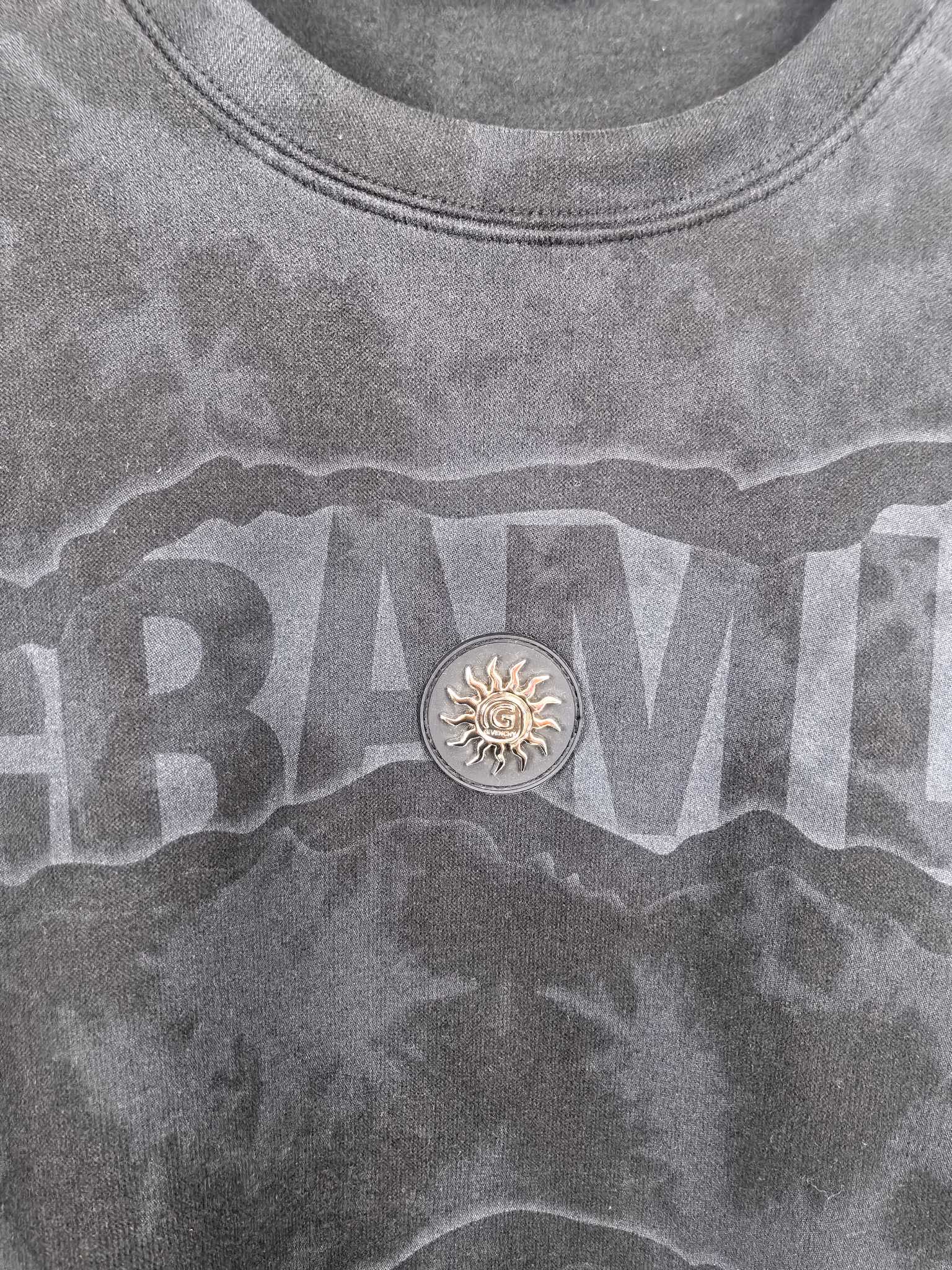 Dark gray crewneck sweatshirt with large front text graphic and round emblem detail
