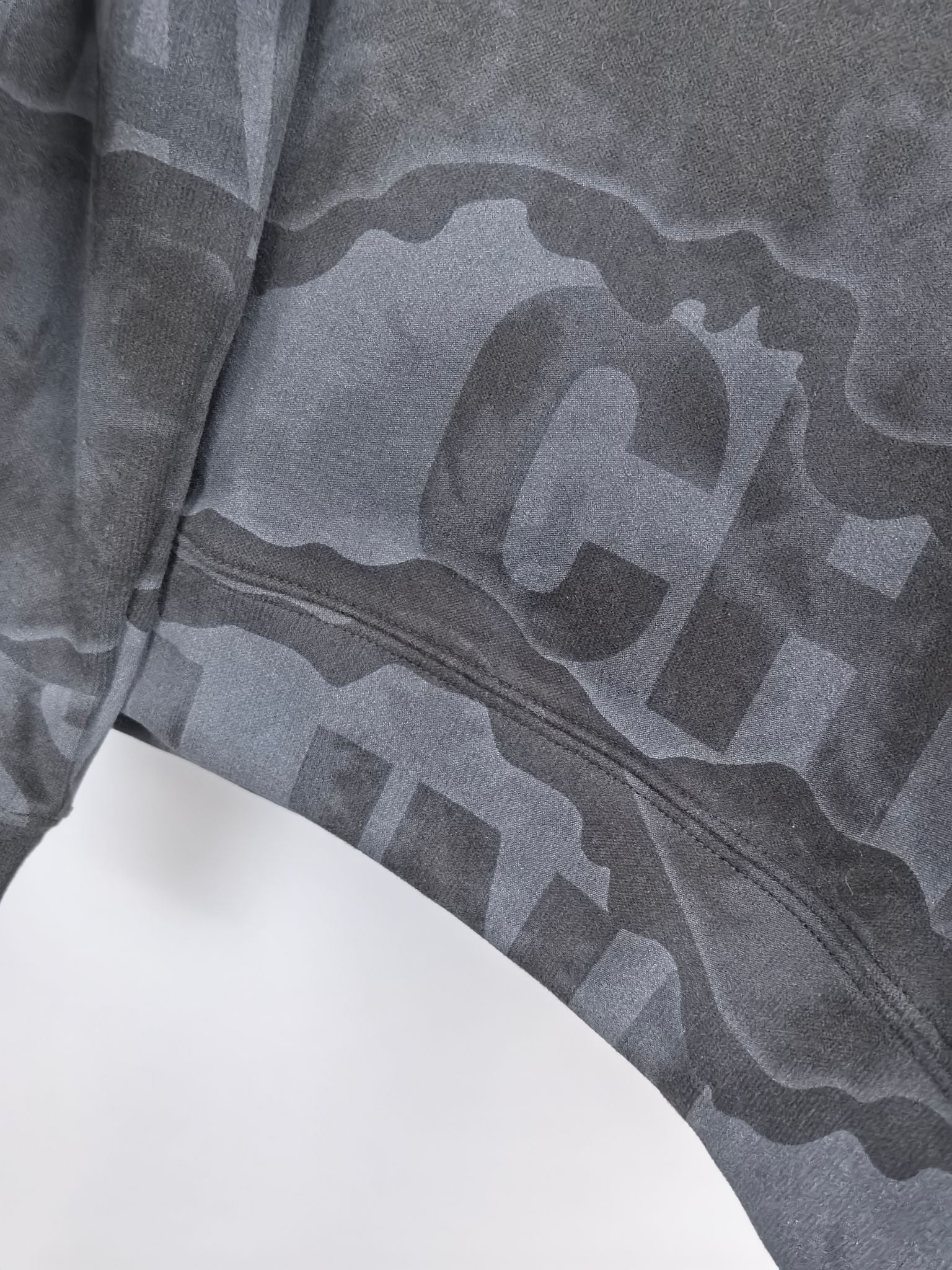 Dark gray crewneck sweatshirt lower sleeve and hem with large camo-style text