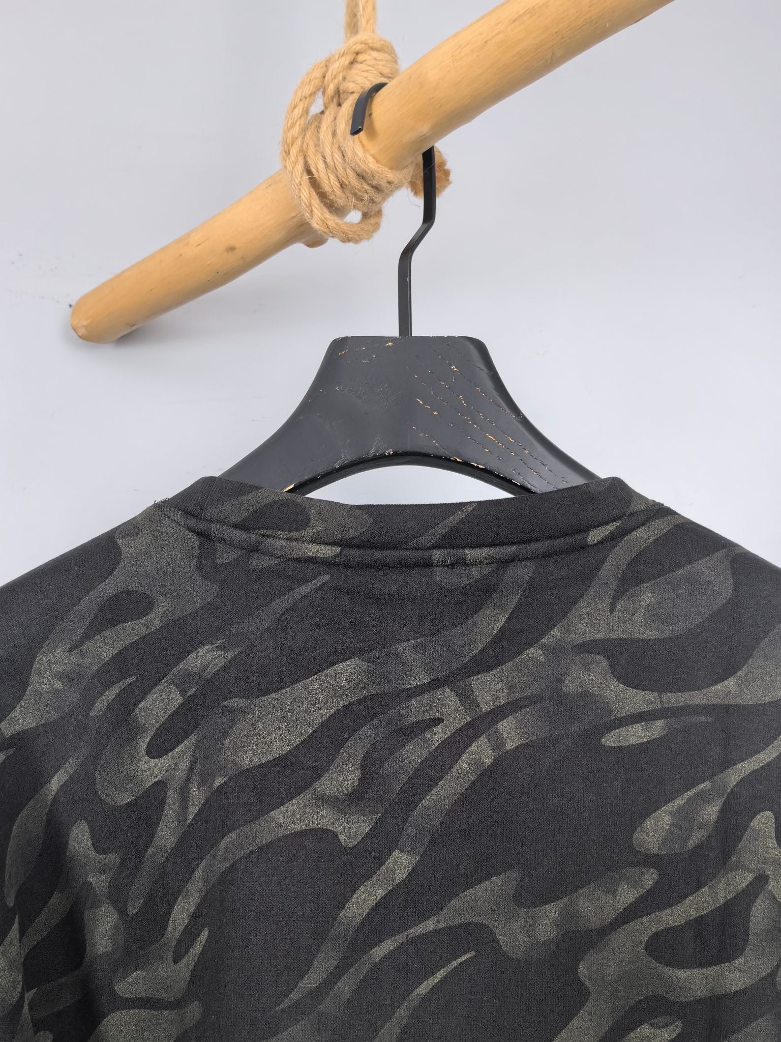 Camo crewneck sweatshirt hanging, close-up of upper chest and collar