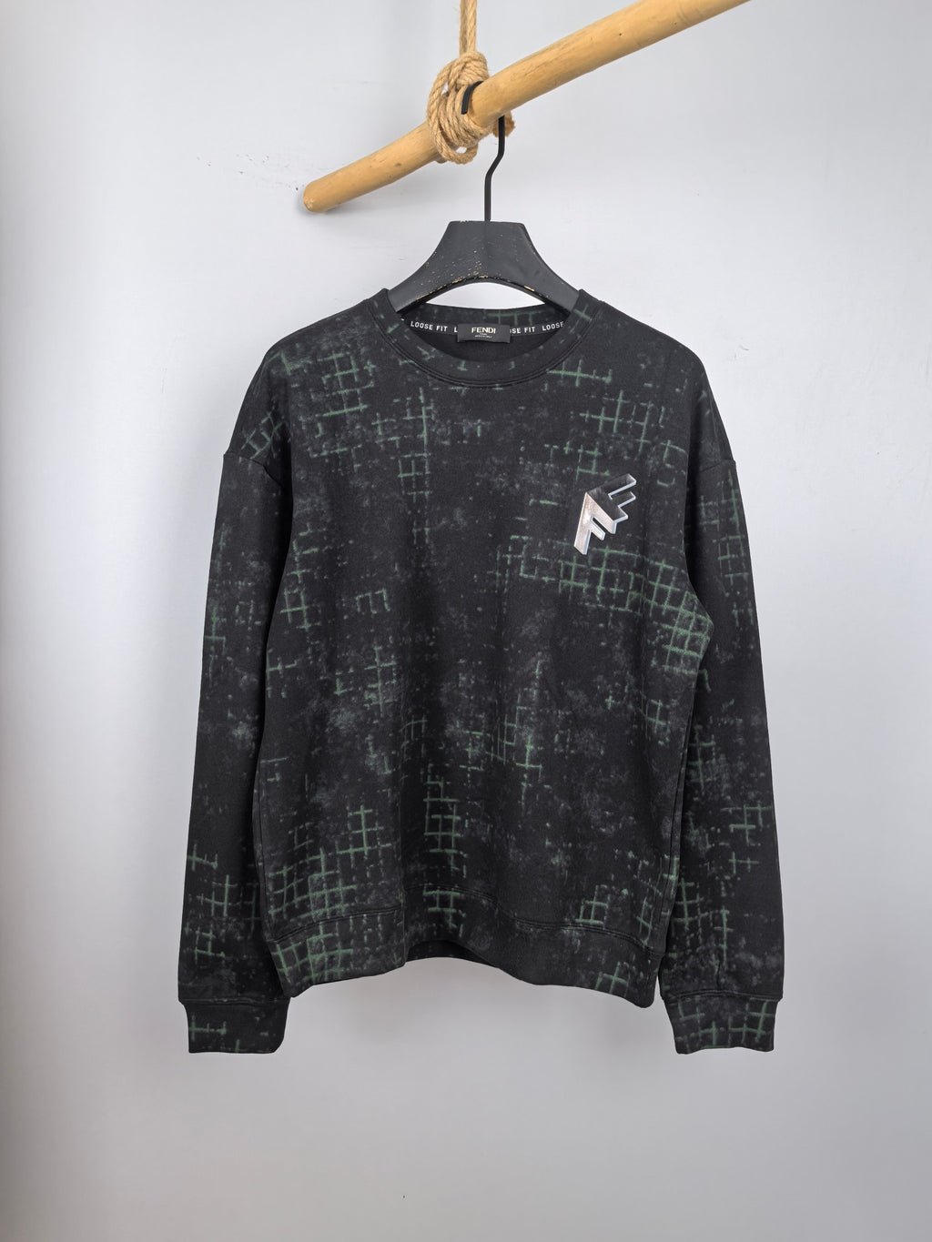 Black long-sleeve sweatshirt with green grid pattern, crew neck and chest logo