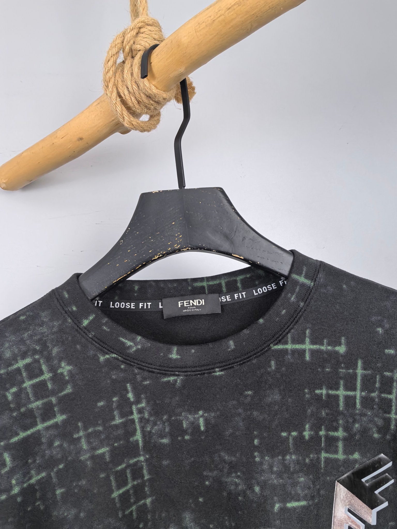 Black sweatshirt neckline with green grid pattern and inner FENDI neck label