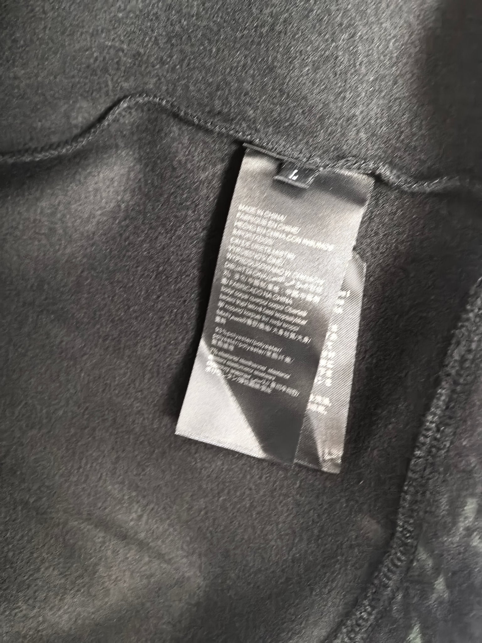 Black sweatshirt with fabric care label tag near inside collar