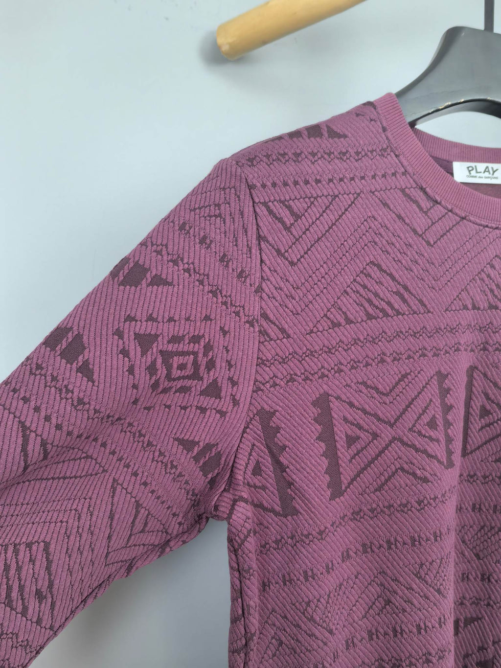 Maroon knit sweater sleeve and shoulder detail with geometric pattern