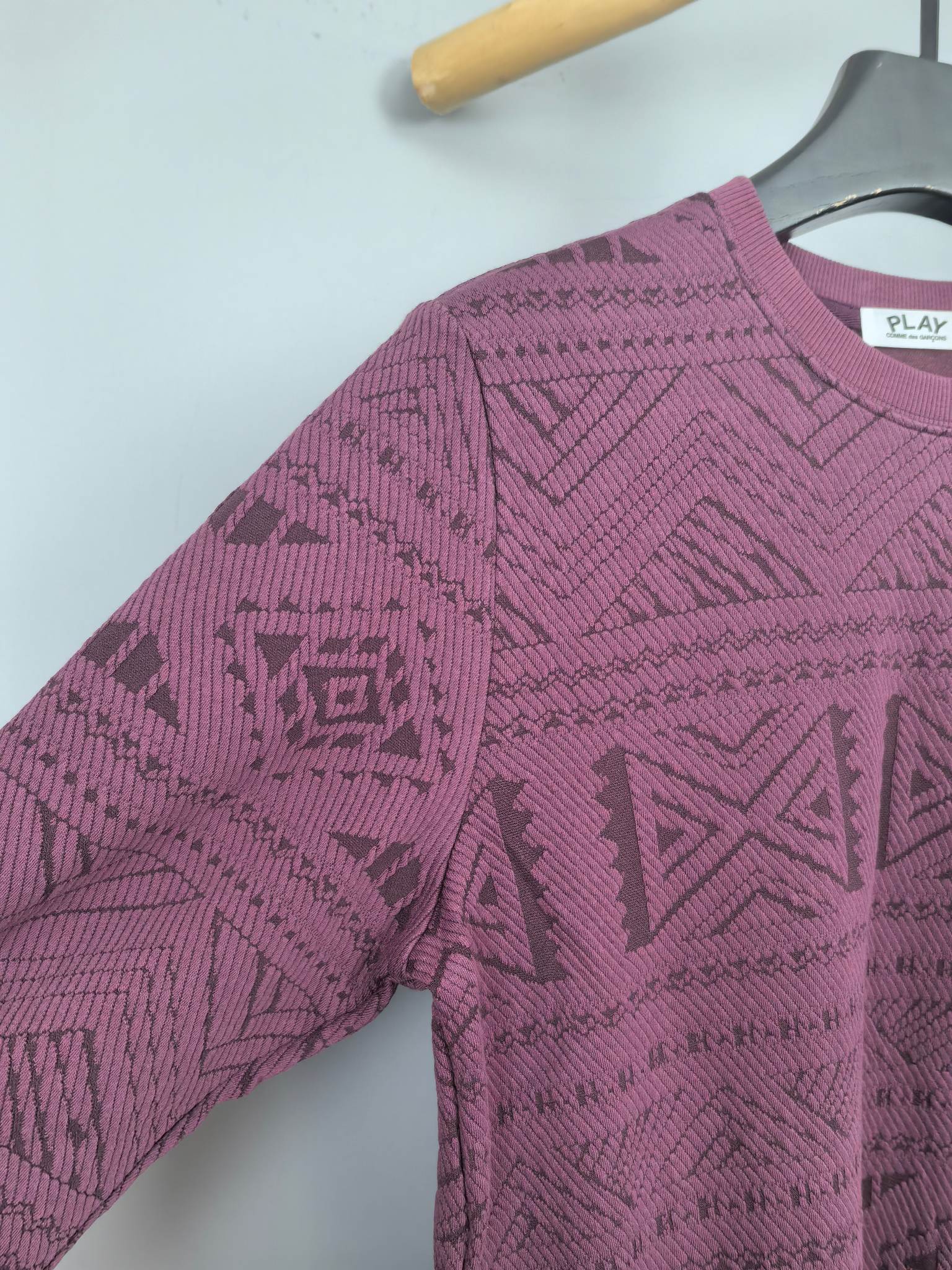 Maroon knit sweater sleeve and shoulder detail with geometric pattern
