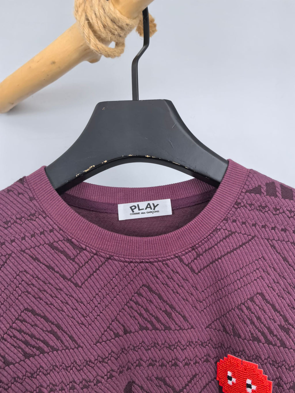 Maroon sweater neckline close-up with PLAY label and red pixel heart patch