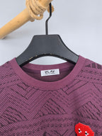 Maroon sweater neckline close-up with PLAY label and red pixel heart patch