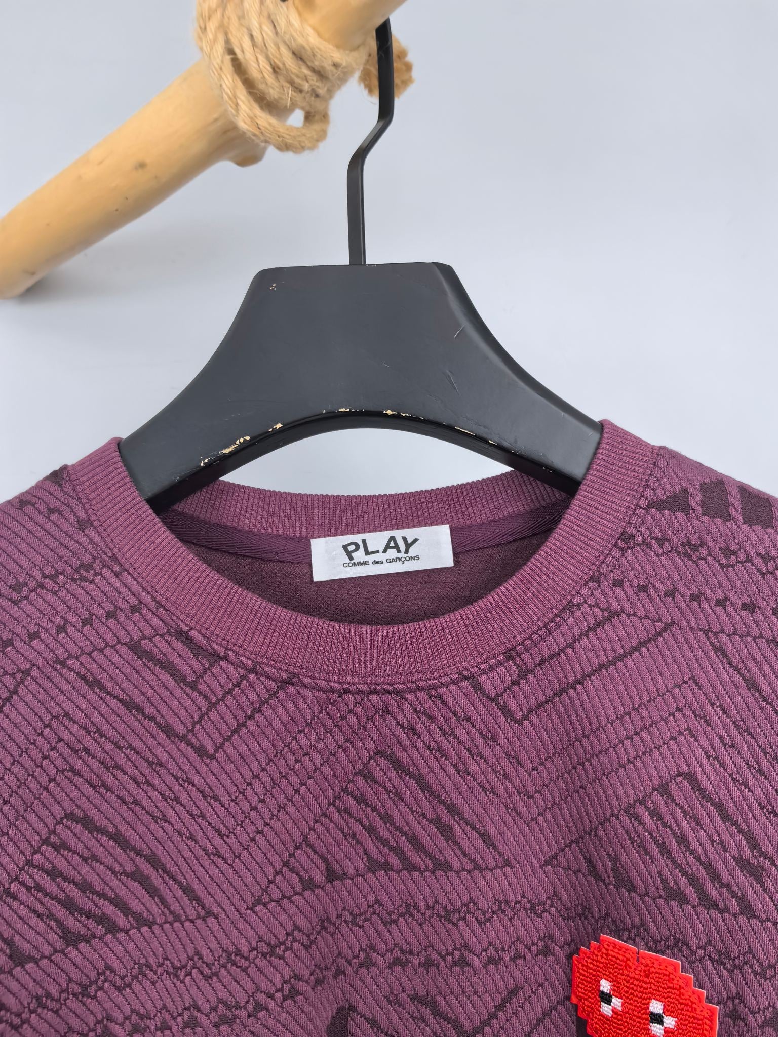 Maroon sweater neckline close-up with PLAY label and red pixel heart patch