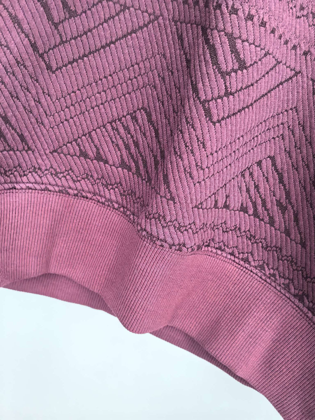 Maroon sweater sleeve cuff detail with textured geometric knit