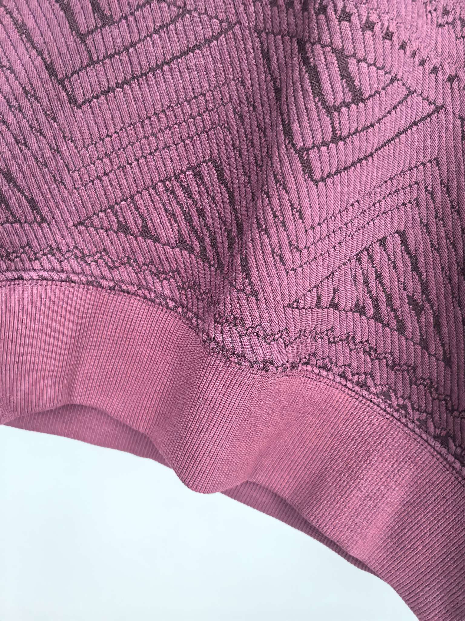 Maroon sweater sleeve cuff detail with textured geometric knit