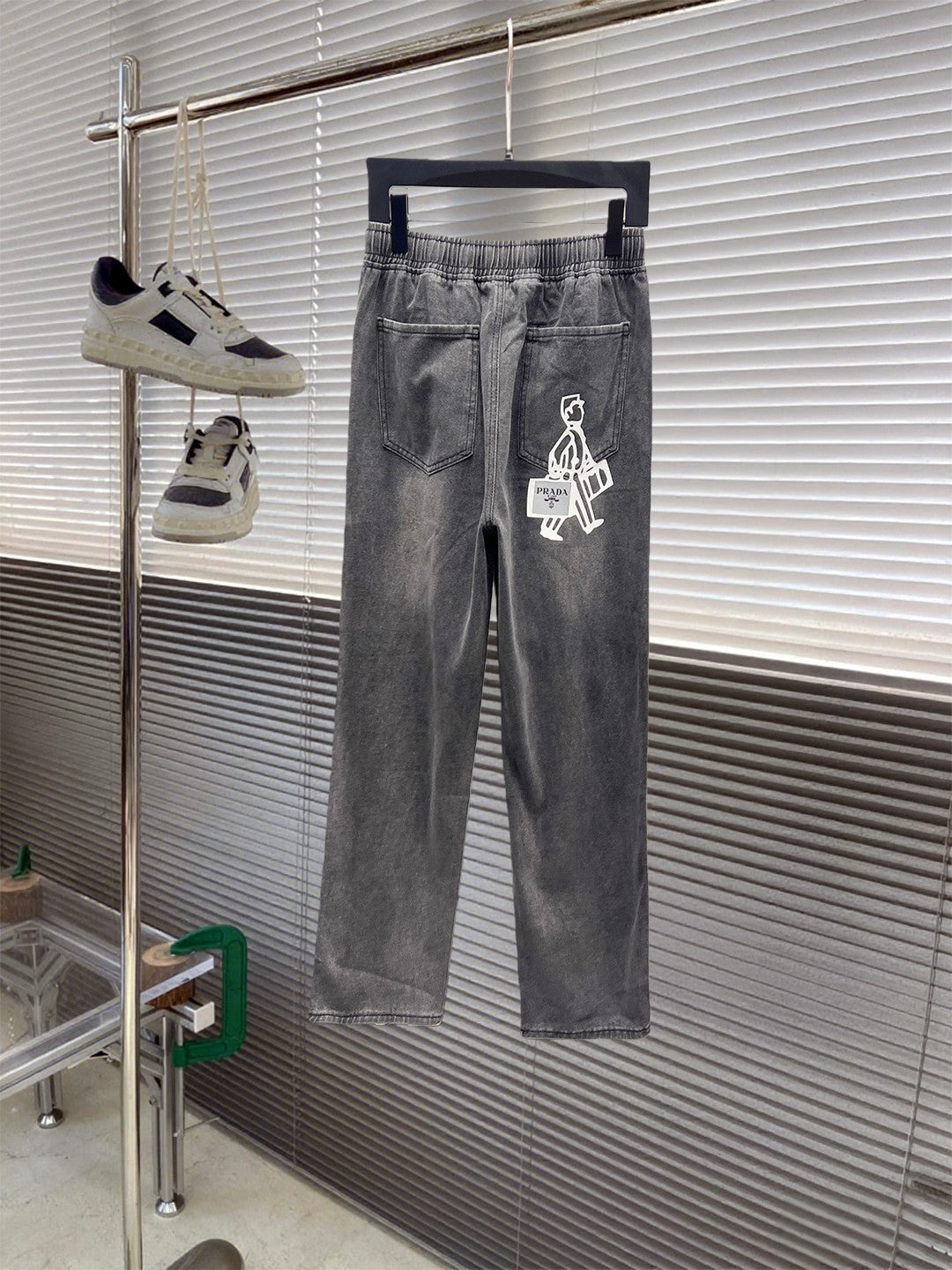 Gray denim pants with elastic waistband, white drawstring, graphic logo patch