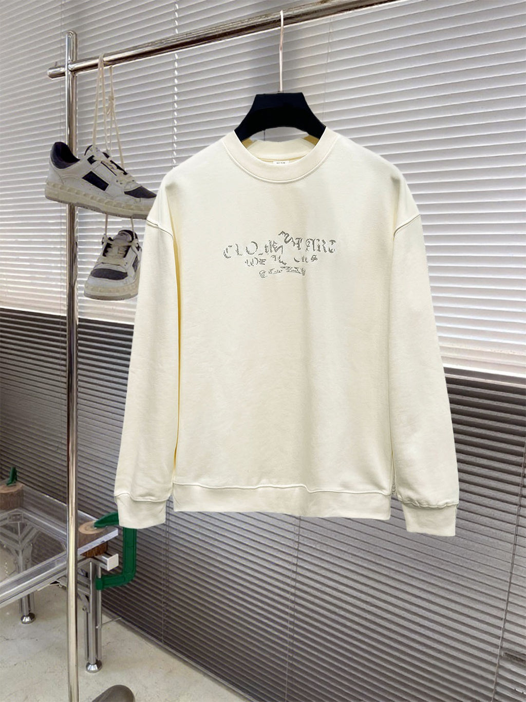Cream long-sleeve crewneck sweatshirt with blue graphic lettering across chest.