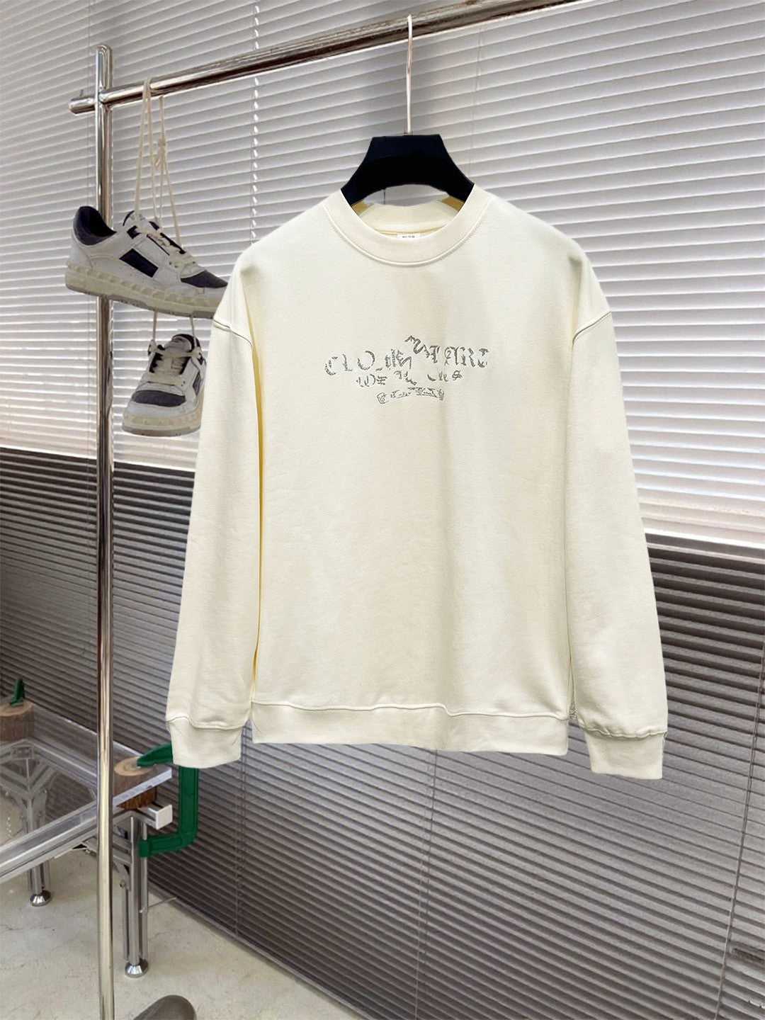 Cream long-sleeve crewneck sweatshirt with blue graphic lettering across chest.