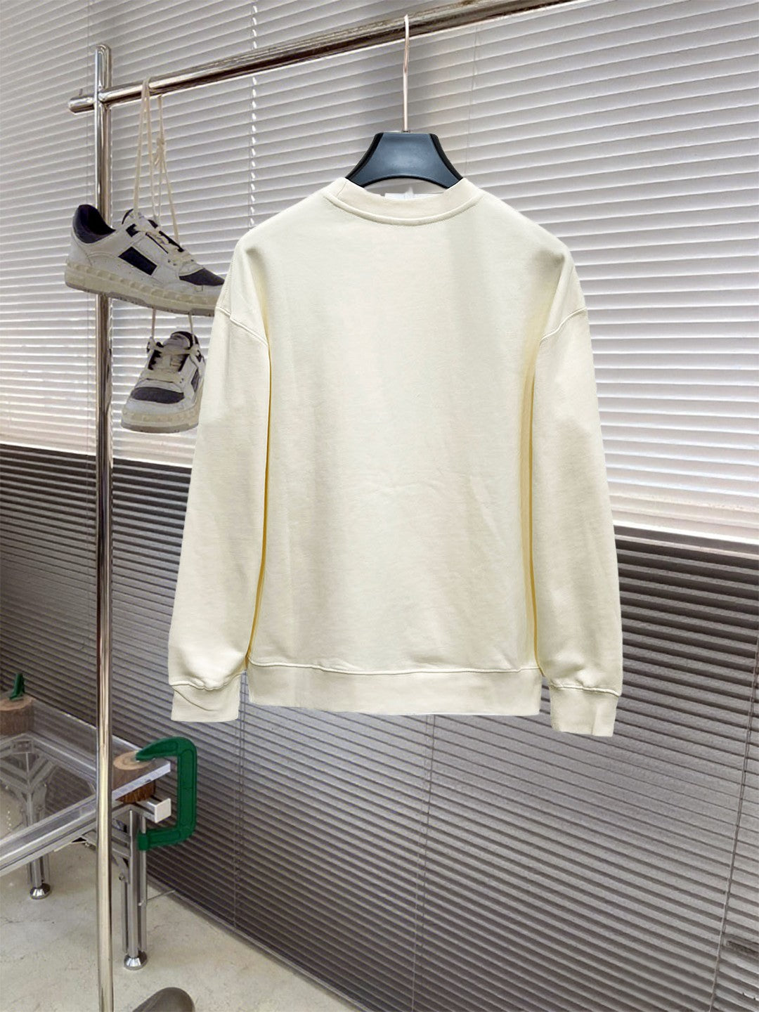 Cream long-sleeve crewneck sweatshirt, back view on hanger; graphic not visible.