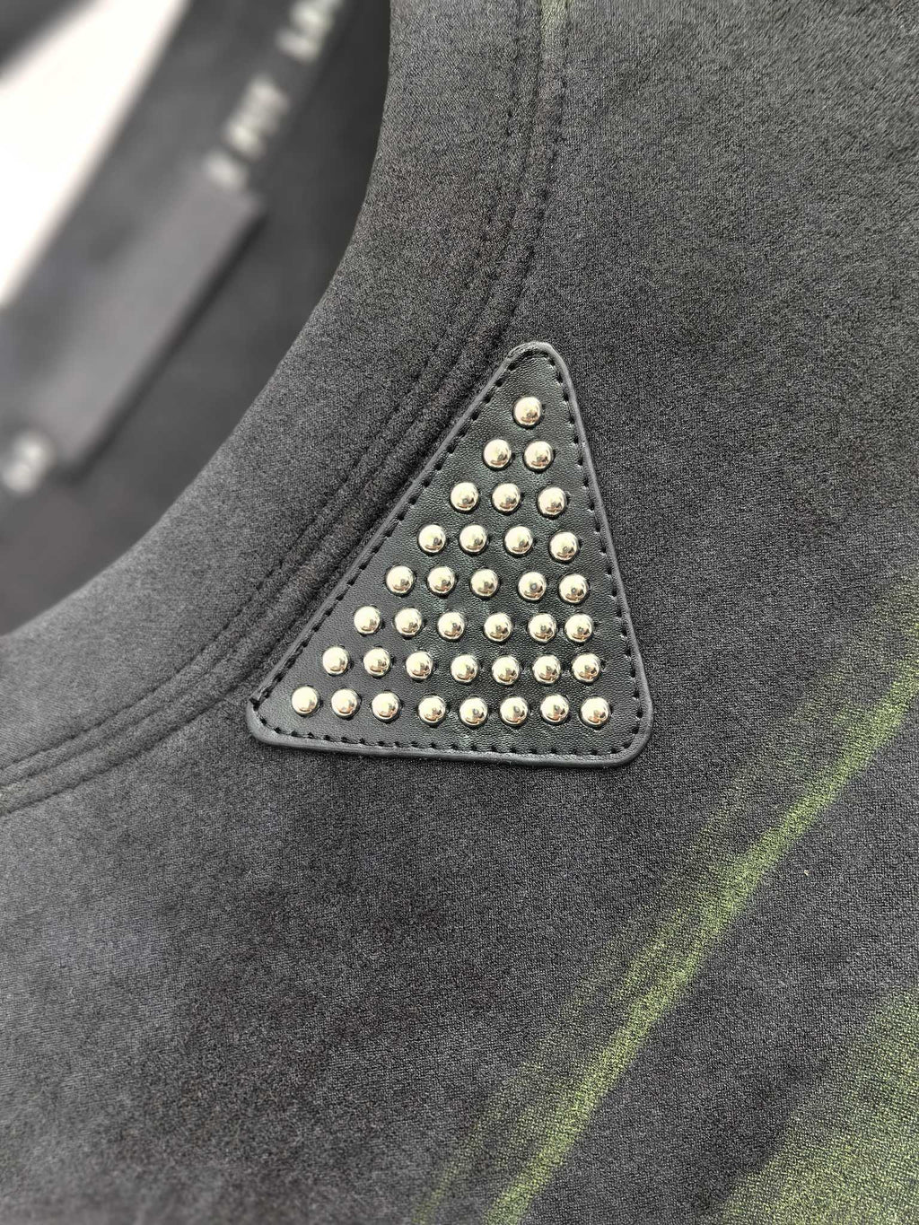Prada sweatshirt chest detail with studded triangle patch, dark gray and green stripes.