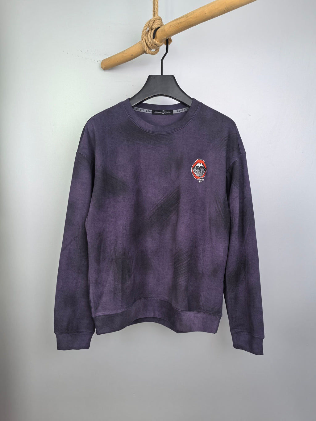 Purple long-sleeve sweatshirt on hanger, front view with small chest patch logo.