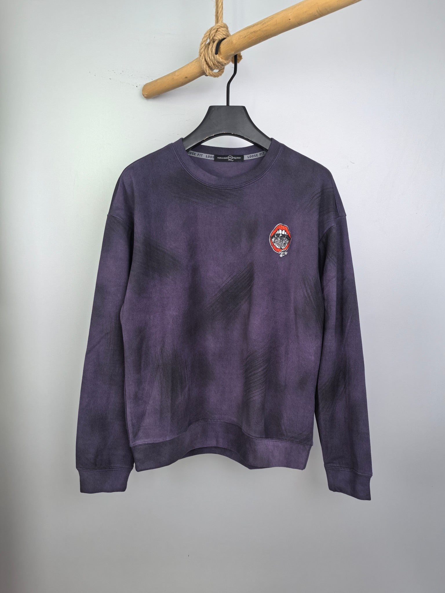 Purple long-sleeve sweatshirt on hanger, front view with small chest patch logo.