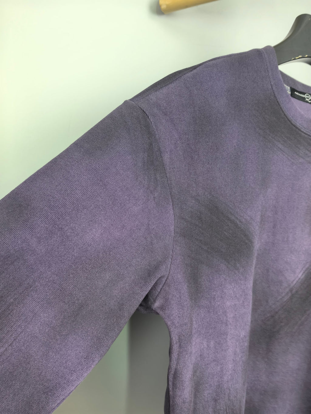 Purple long-sleeve sweatshirt with side seam detail near hip.