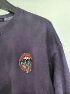 Purple sweatshirt with embroidered circular patch on left chest.