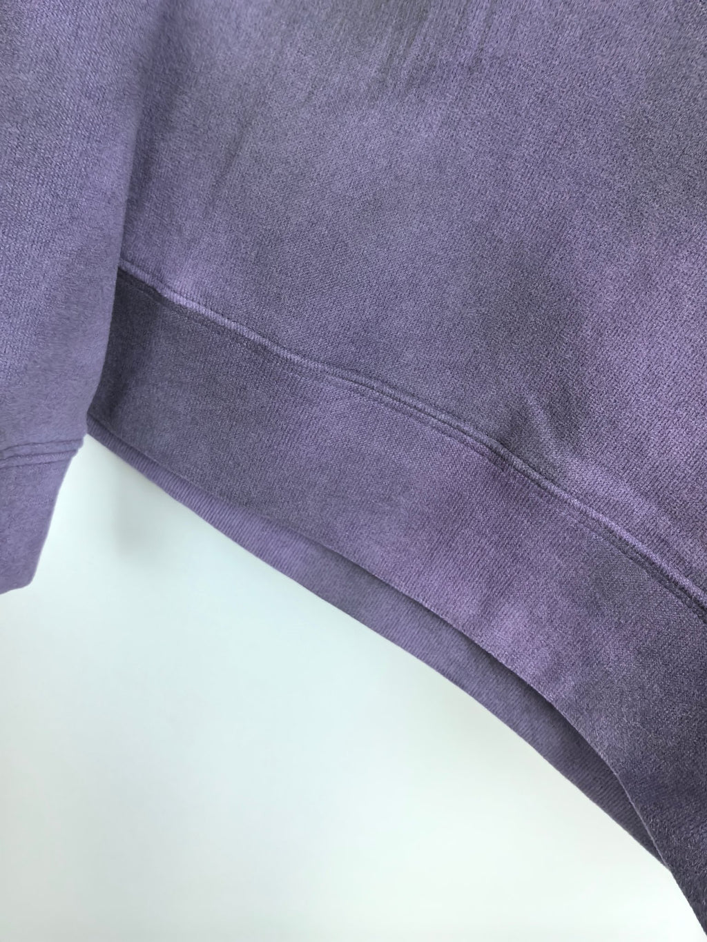 Purple sweatshirt ribbed waistband and stitched hem edge detail.