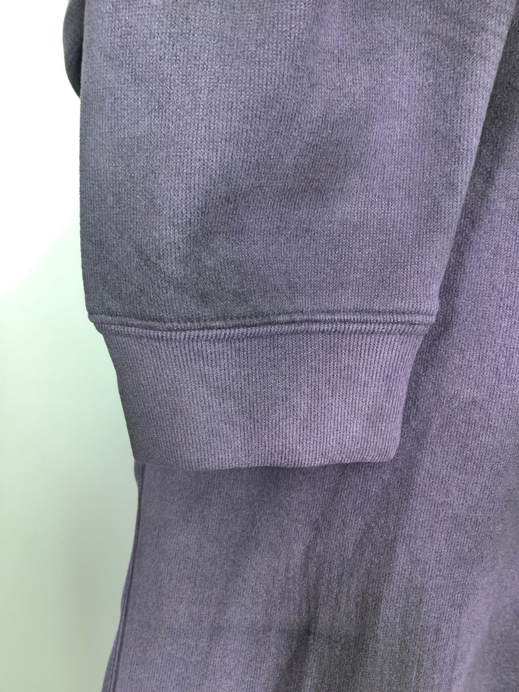 Purple sweatshirt sleeve cuff and ribbed hem detail on hanger.