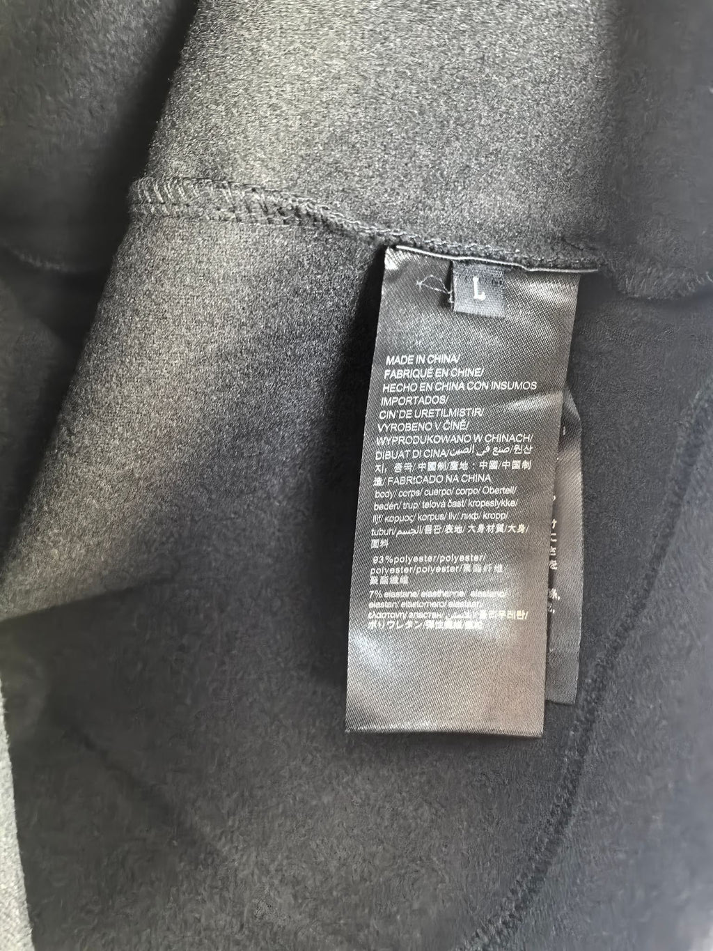 Long-sleeve crewneck shirt care label inside collar, dark charcoal fabric tag