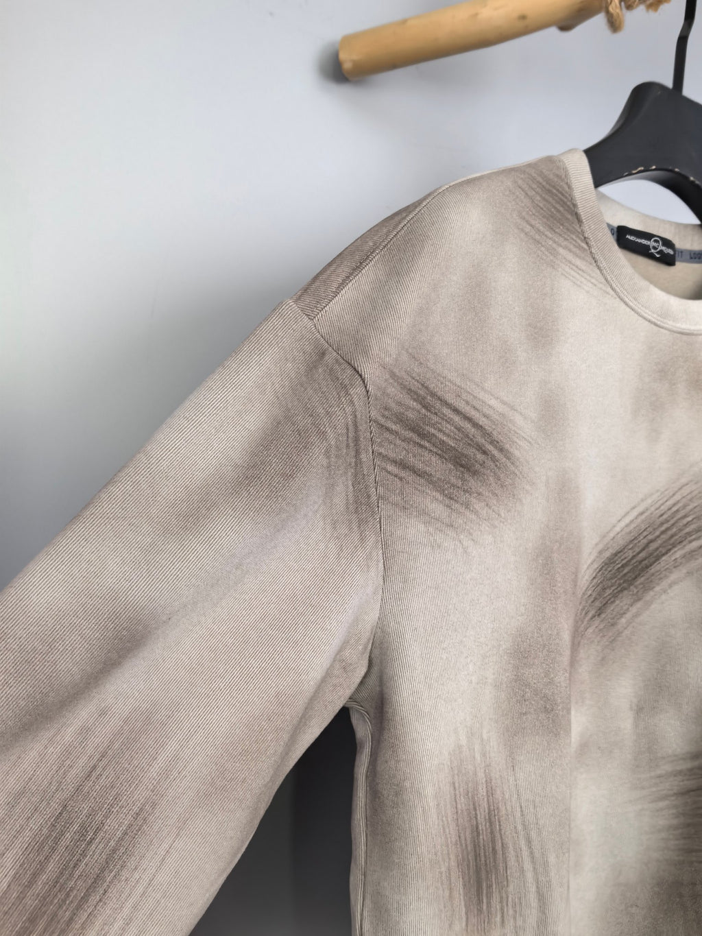 Light beige long-sleeve sweatshirt with side seam detail on hanger.