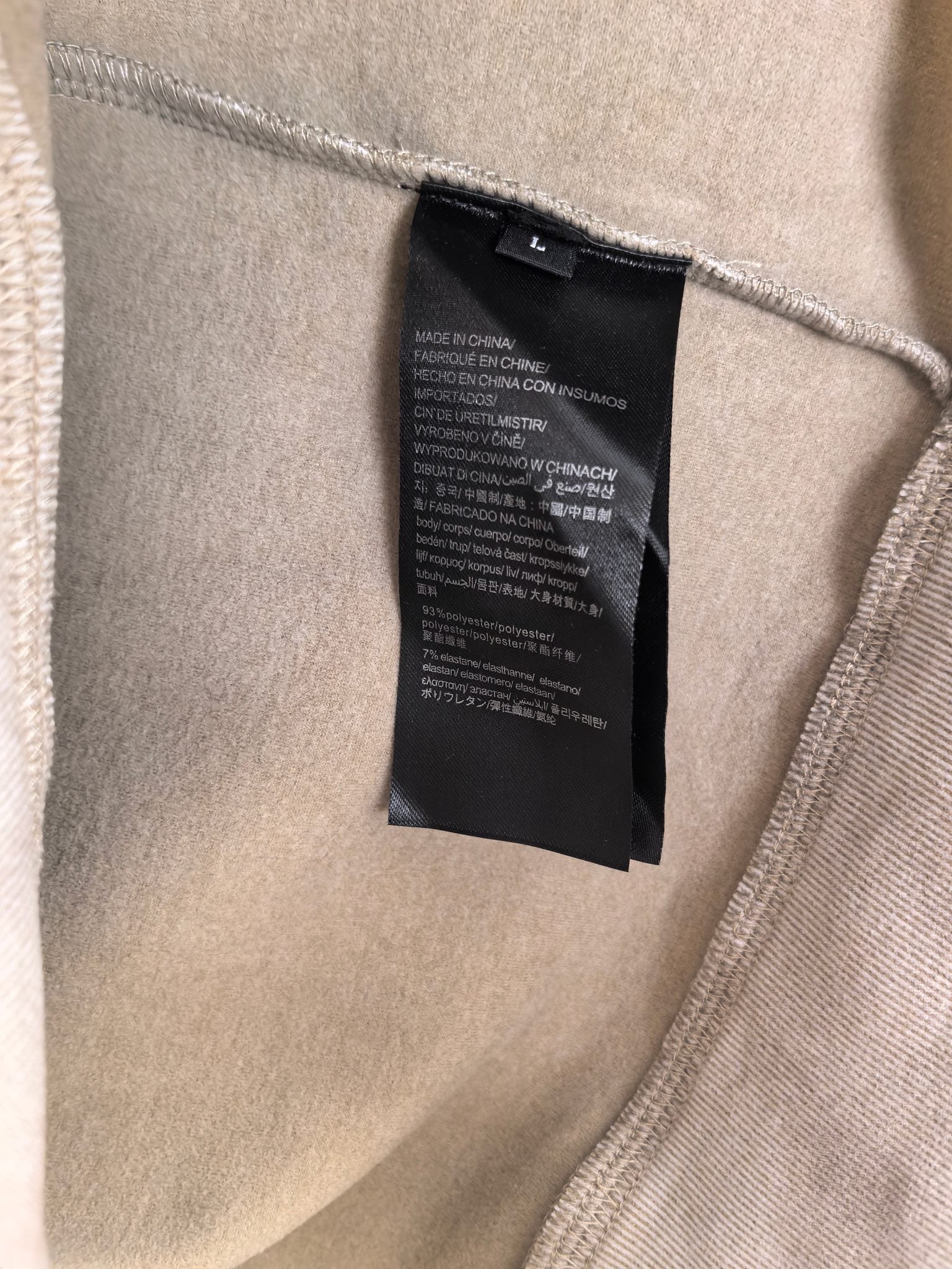 Light beige sweatshirt interior: black care label sewn at side seam.