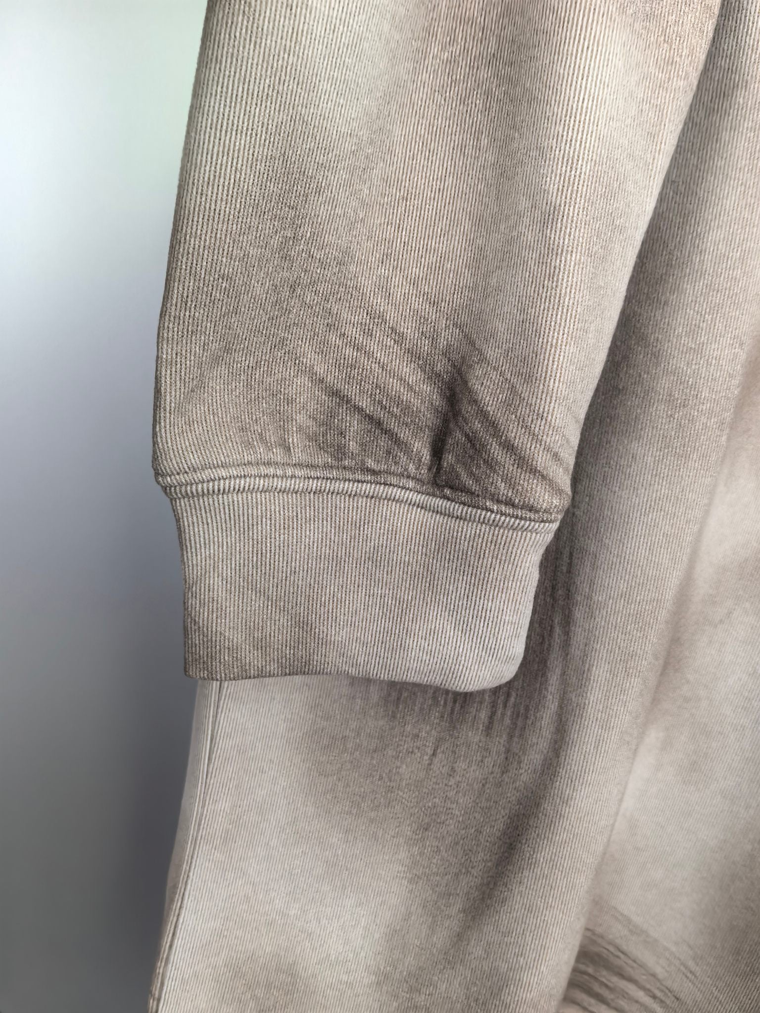 Light beige sweatshirt sleeve cuff and hem with ribbed trim detail.
