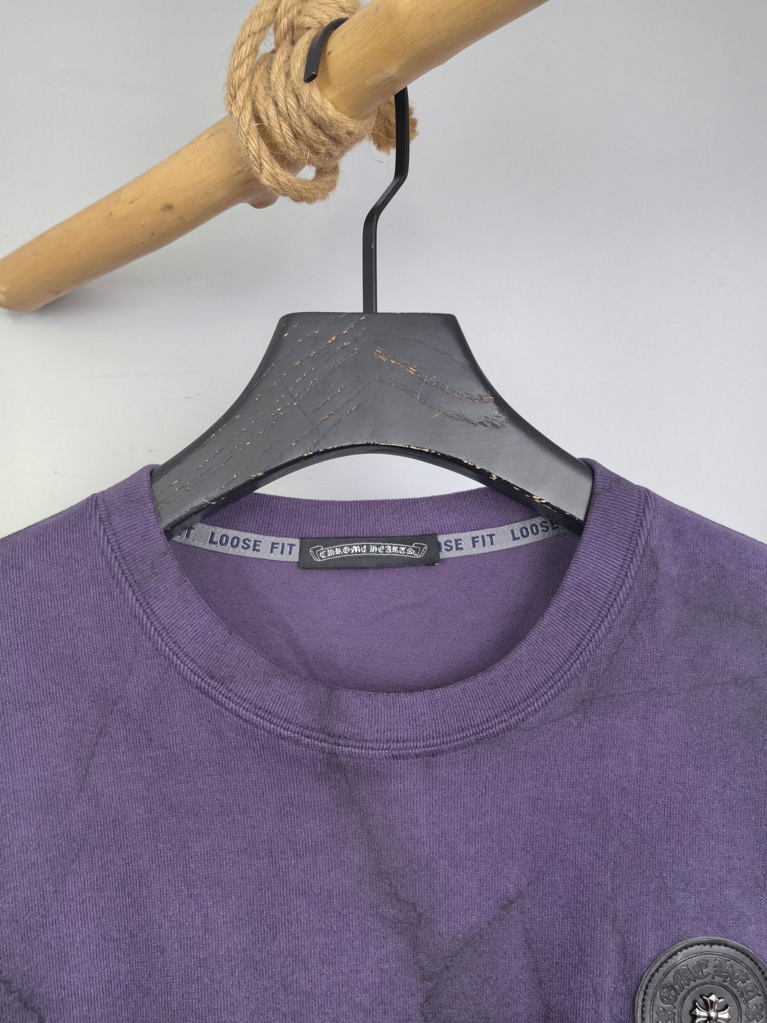 Purple crewneck sweatshirt neckline and collar label detail on hanger