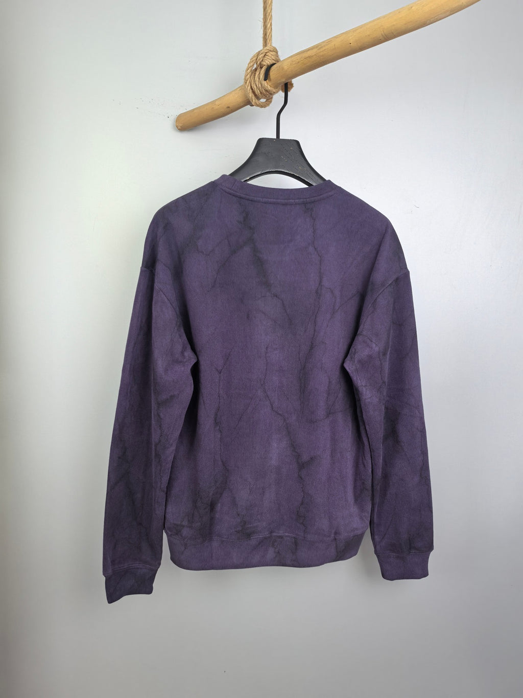 Purple long-sleeve crewneck sweatshirt with textured print, hanging on hanger