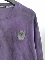 Purple crewneck sweatshirt with round decorative patch on the chest