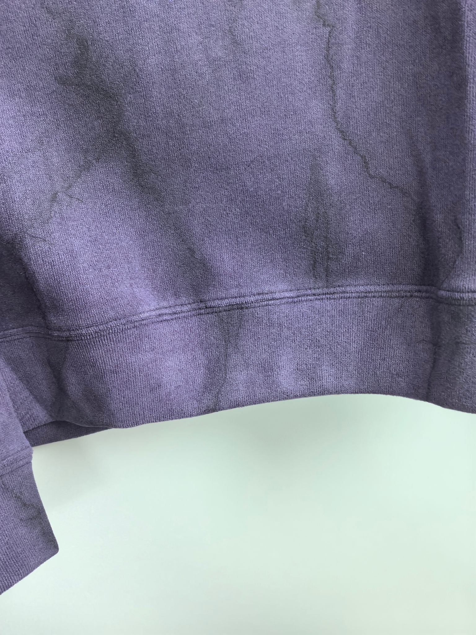 Purple sweatshirt back panel with ribbed hem and faint fabric texture