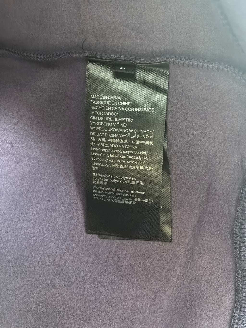 Inside neck label on purple sweatshirt with care and origin text