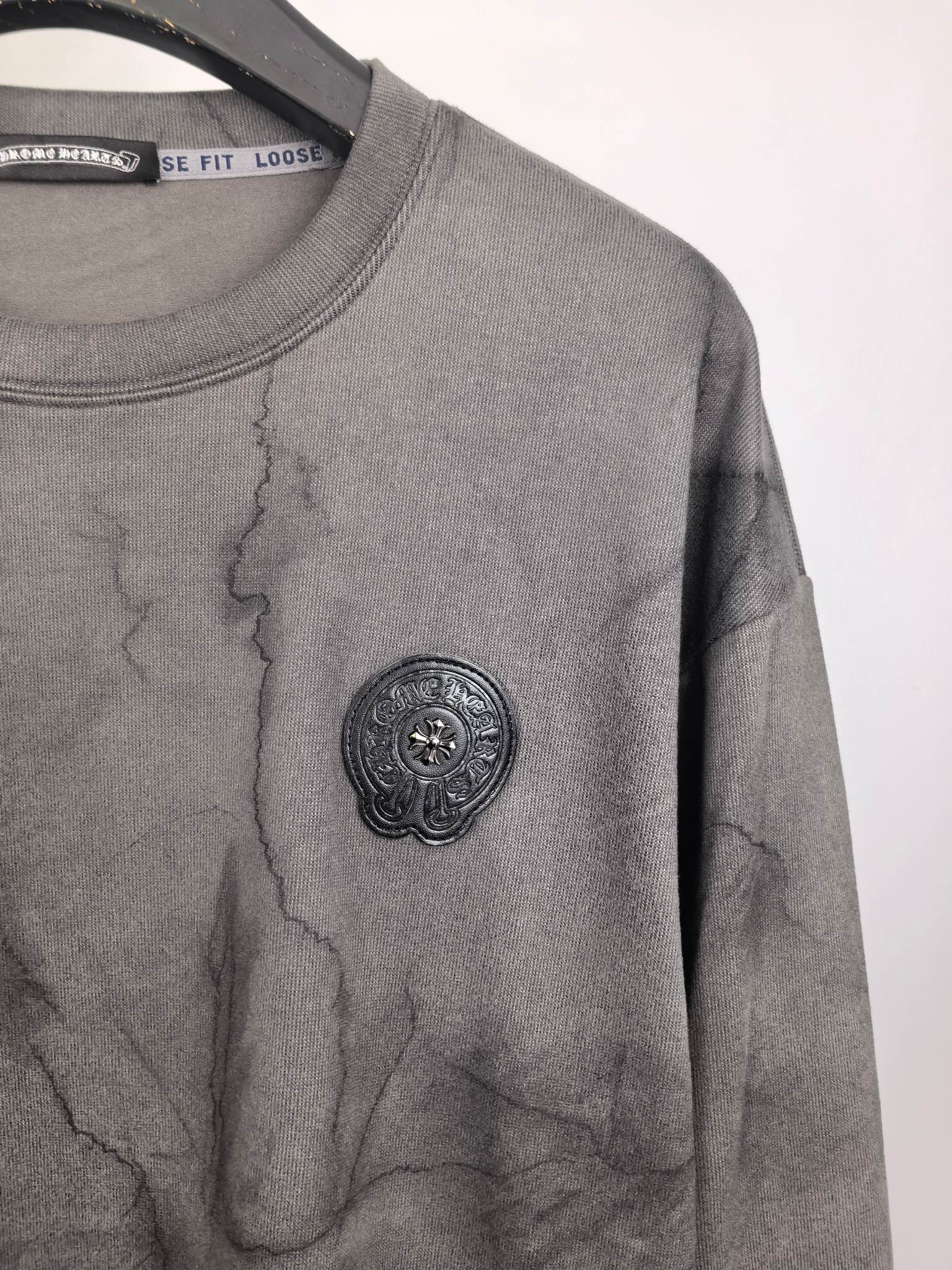 Dark gray marble crewneck sweatshirt with round embossed-style logo on chest