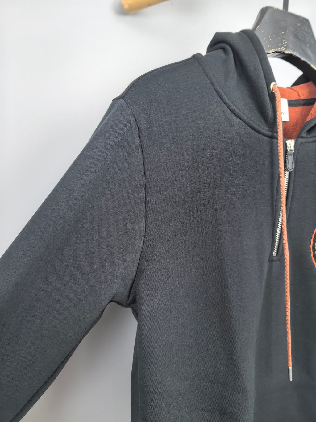 Dark gray hoodie with front zipper and orange drawstring ties at collar