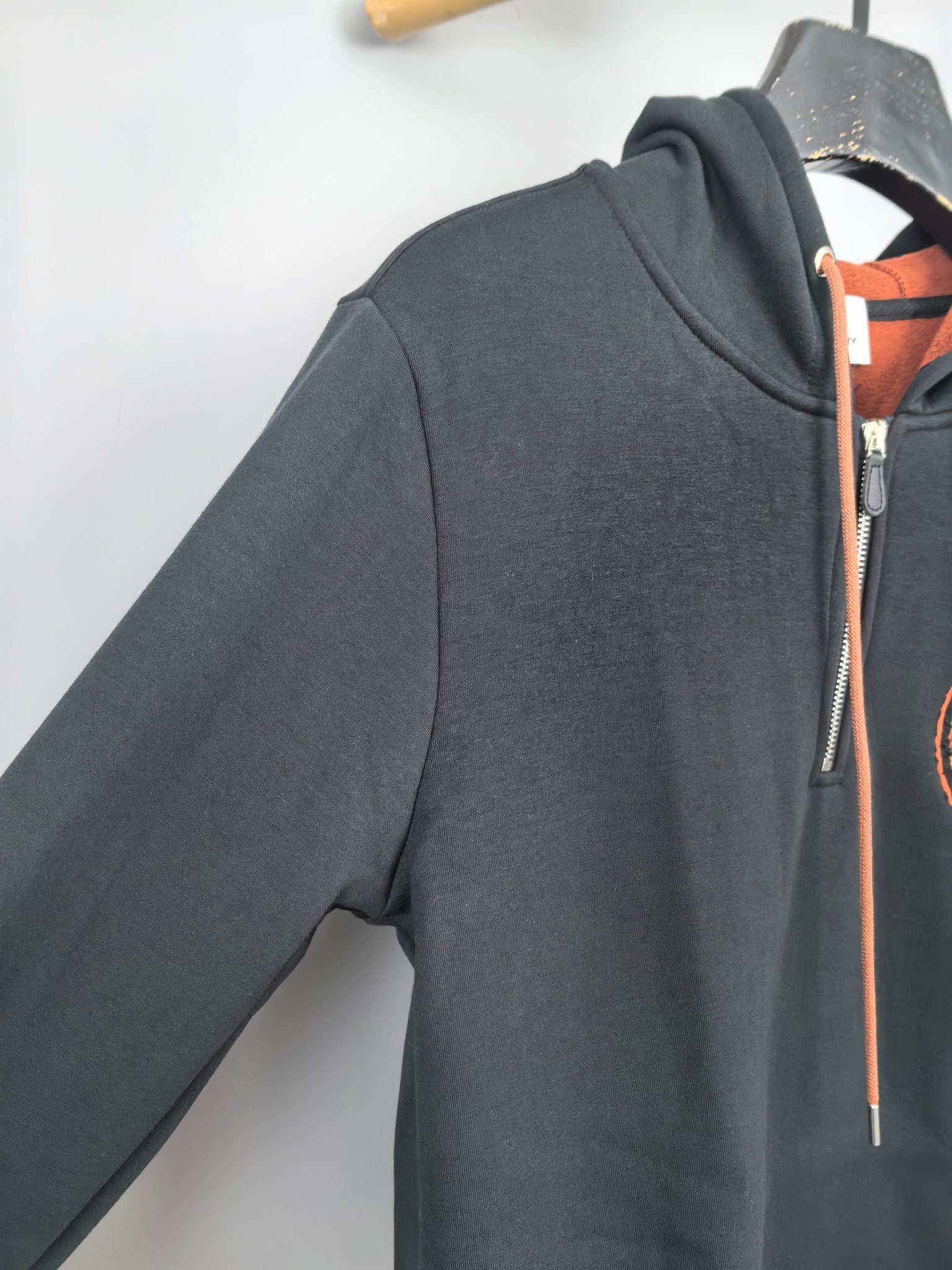 Dark gray hoodie with front zipper and orange drawstring ties at collar