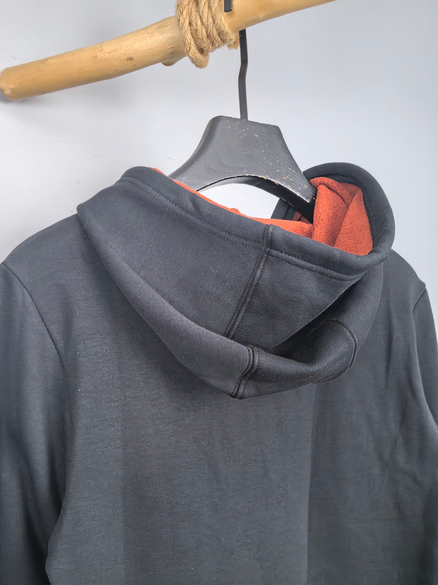 Dark gray hoodie back with orange hood lining and ribbed collar