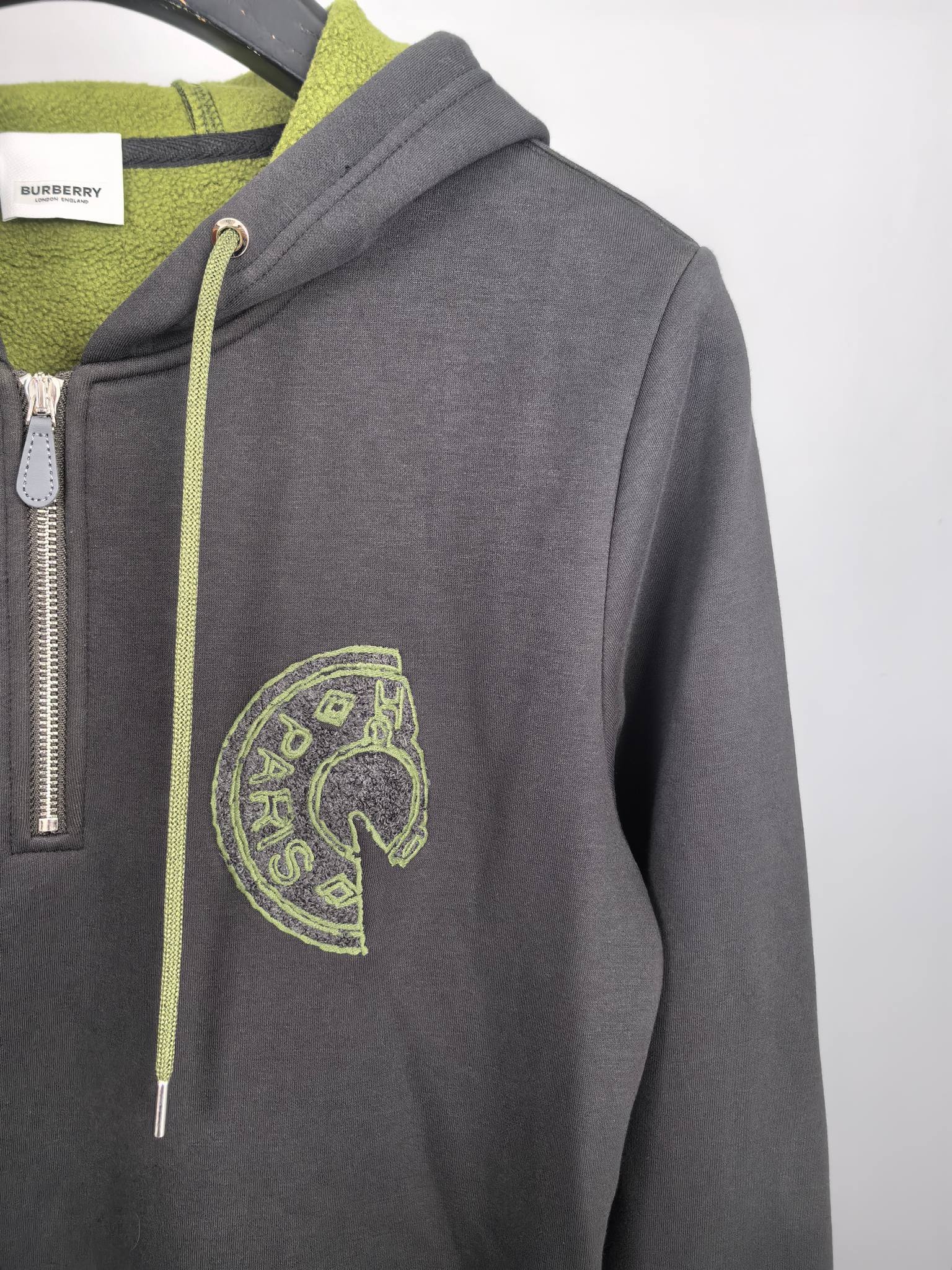 Dark gray zip-up hoodie with neon green embroidered logo on the chest