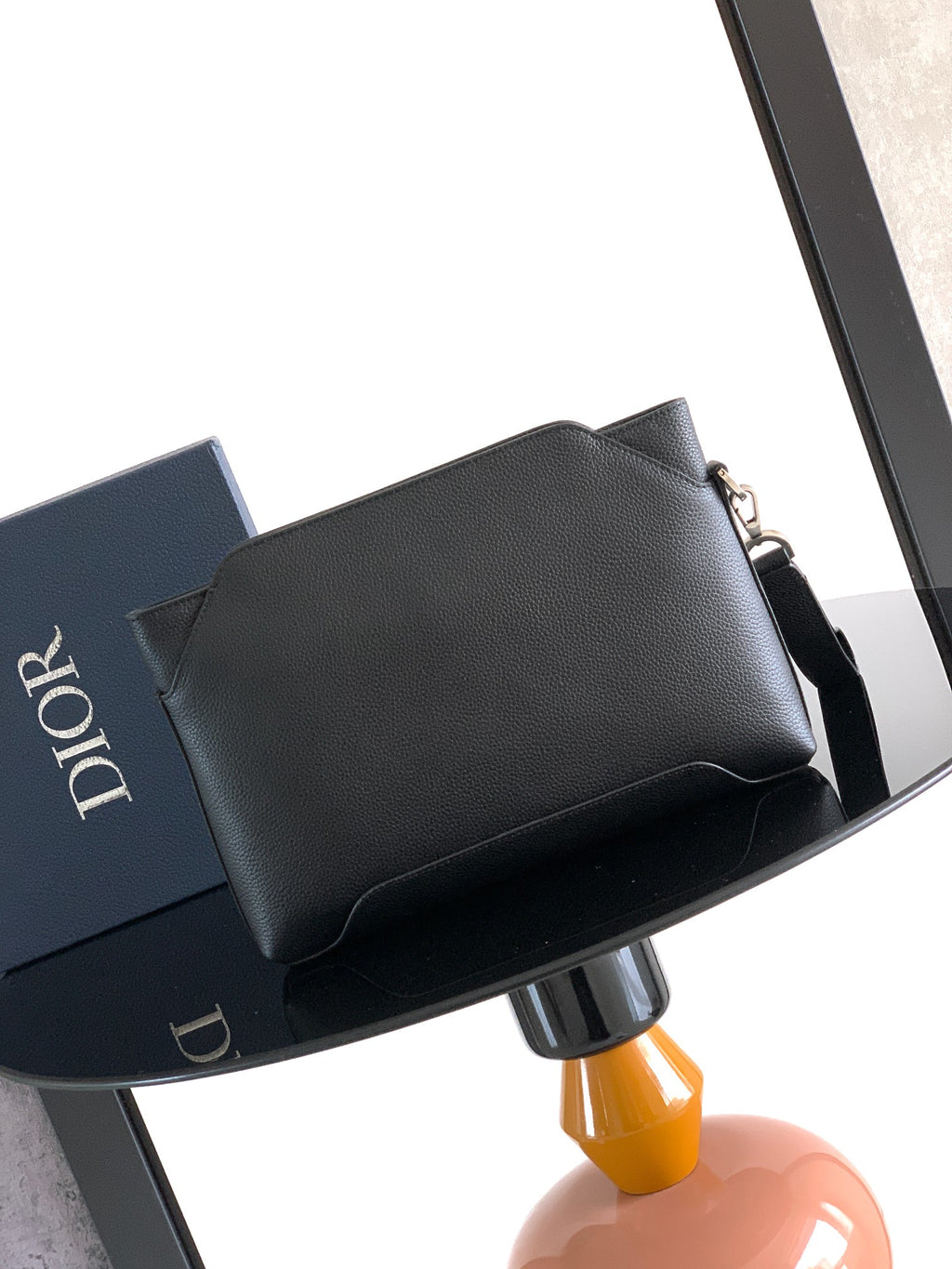 Black Dior men's small bag with structured top flap and side buckle strap.