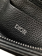 Black Dior leather bag with embossed DIOR logo on pebbled texture.